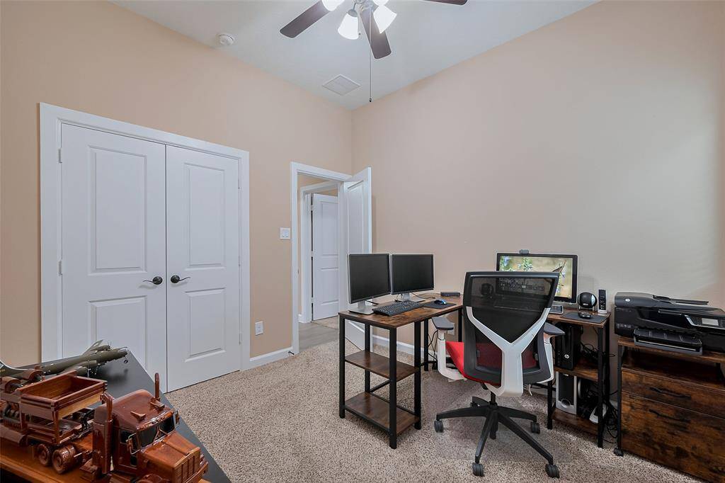 This bedroom/office features a ceiling fan for comfort. There's a closet with double doors and additional shelves for storage, perfect for a productive work-from-home environment.