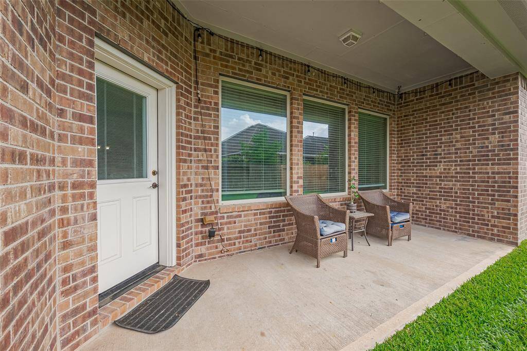 This photo showcases a cozy patio area with brick walls and covered space with a grassy edge, perfect for relaxing outdoors.