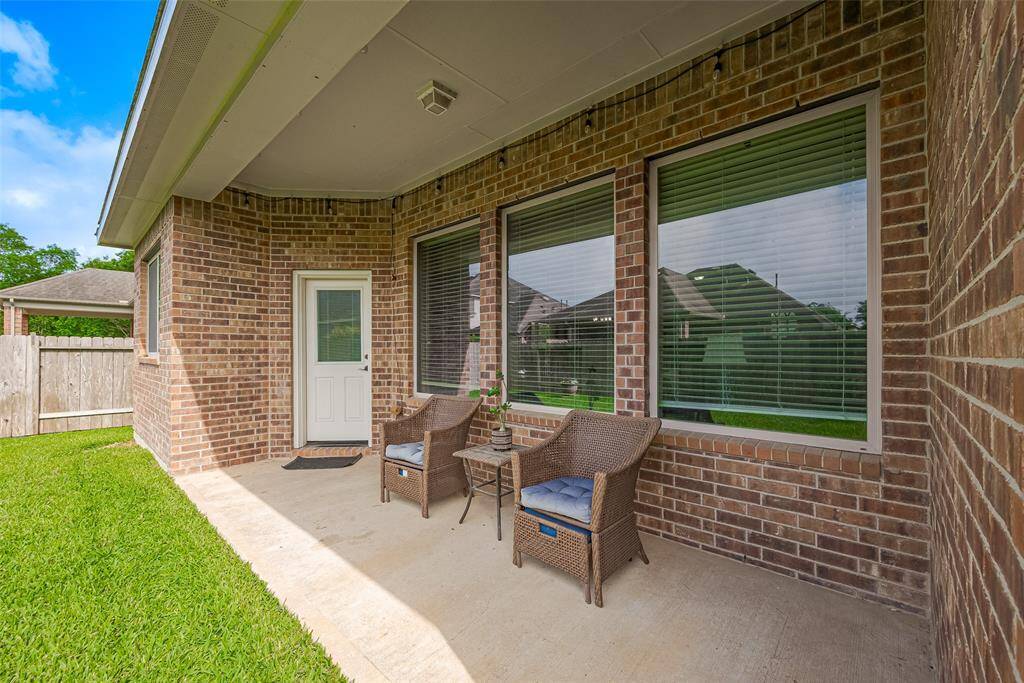 The patio opens to a grassy yard, enclosed by a wooden fence, perfect for privacy and outdoor enjoyment.