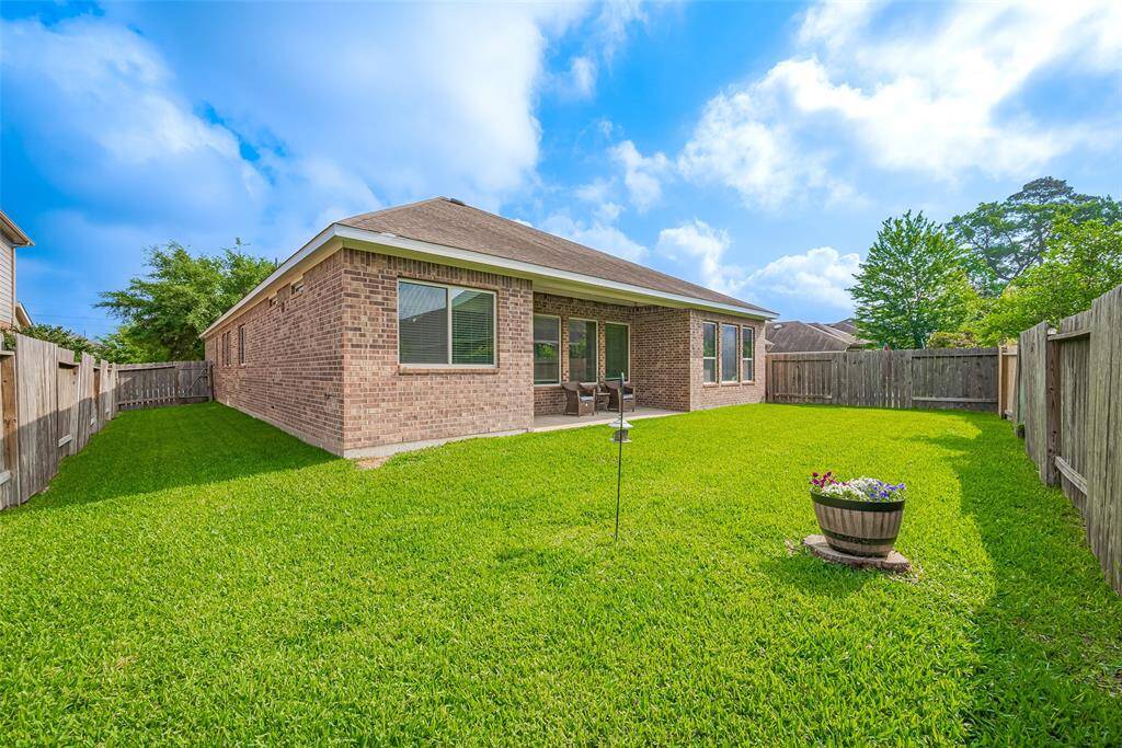 This photo showcases a charming brick home with a spacious, well-maintained backyard. The yard features lush green grass, a wooden fence for privacy, perfect for outdoor activities and relaxation.