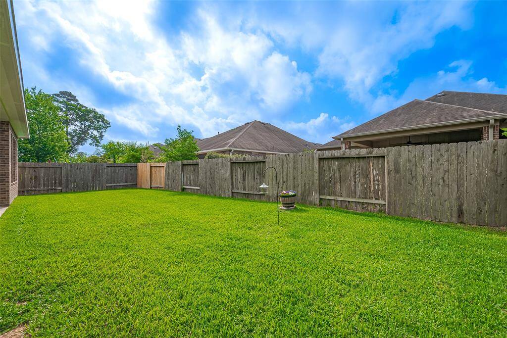 Spacious backyard with lush green grass, enclosed by a wooden fence, perfect for outdoor activities and privacy.