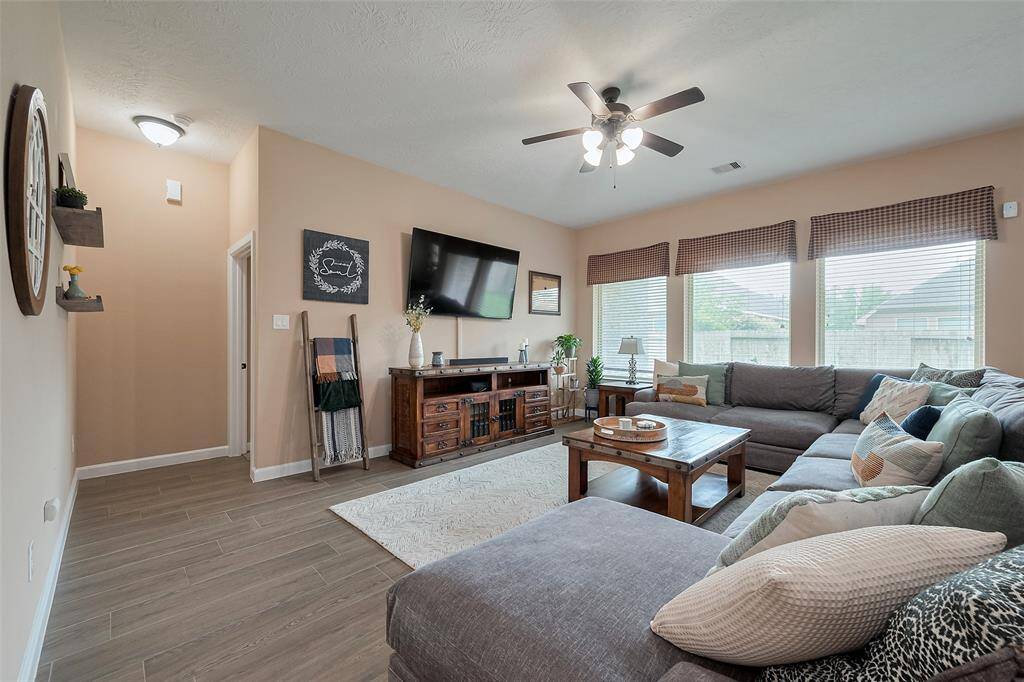 Bright and welcoming living room with large windows, neutral walls, and wood-look flooring. Ideal for family gatherings and relaxation.