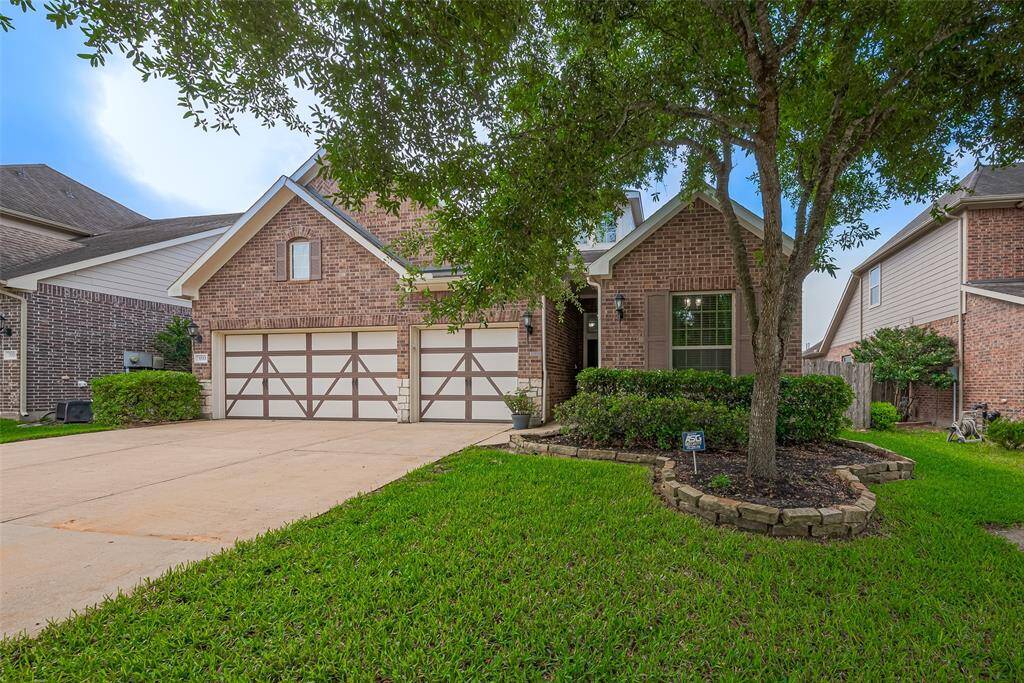 This charming brick home features a spacious three-car garage, a well-maintained front yard with mature trees, and a welcoming pathway leading to the entrance. Ideal for families, it offers both curb appeal and functionality.