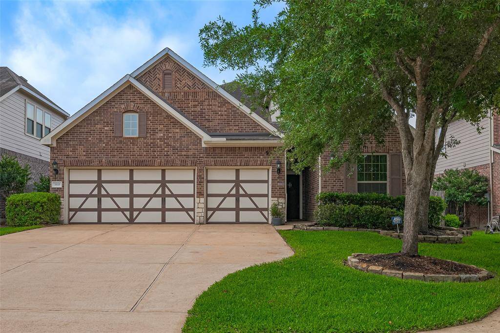This photo showcases a charming brick home with a three-car garage and double driveway.