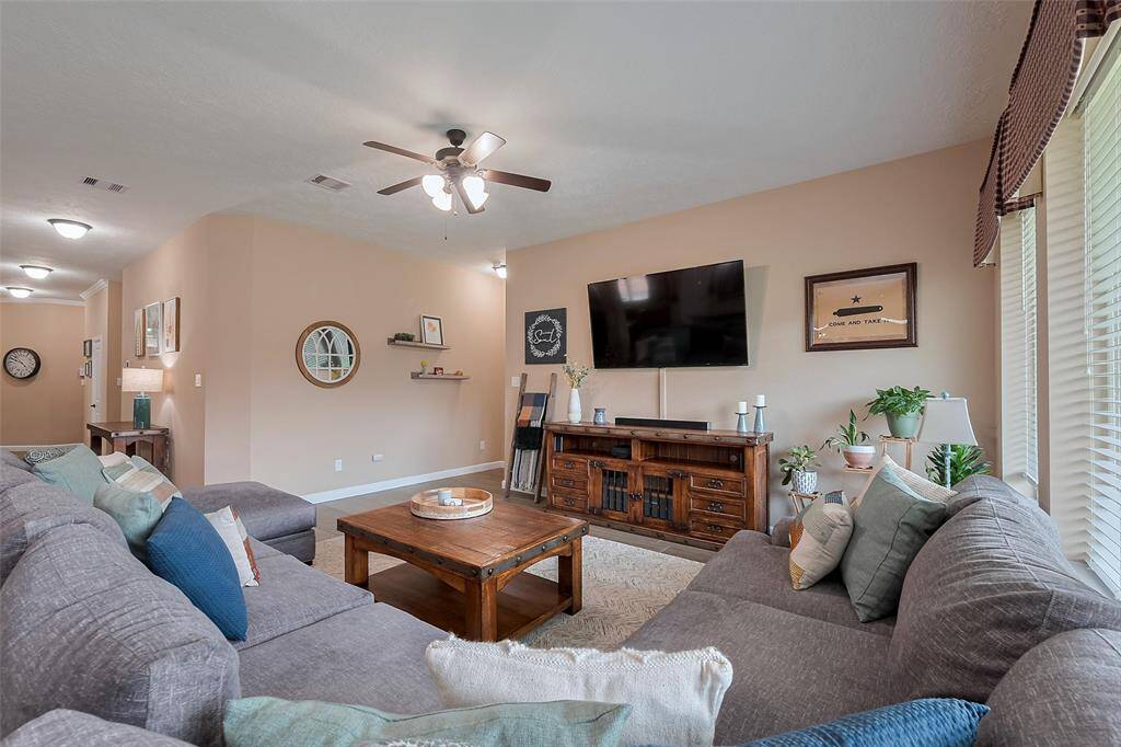 The room is well-lit with ceiling lights and a fan, and has large windows for natural light, creating a cozy atmosphere.