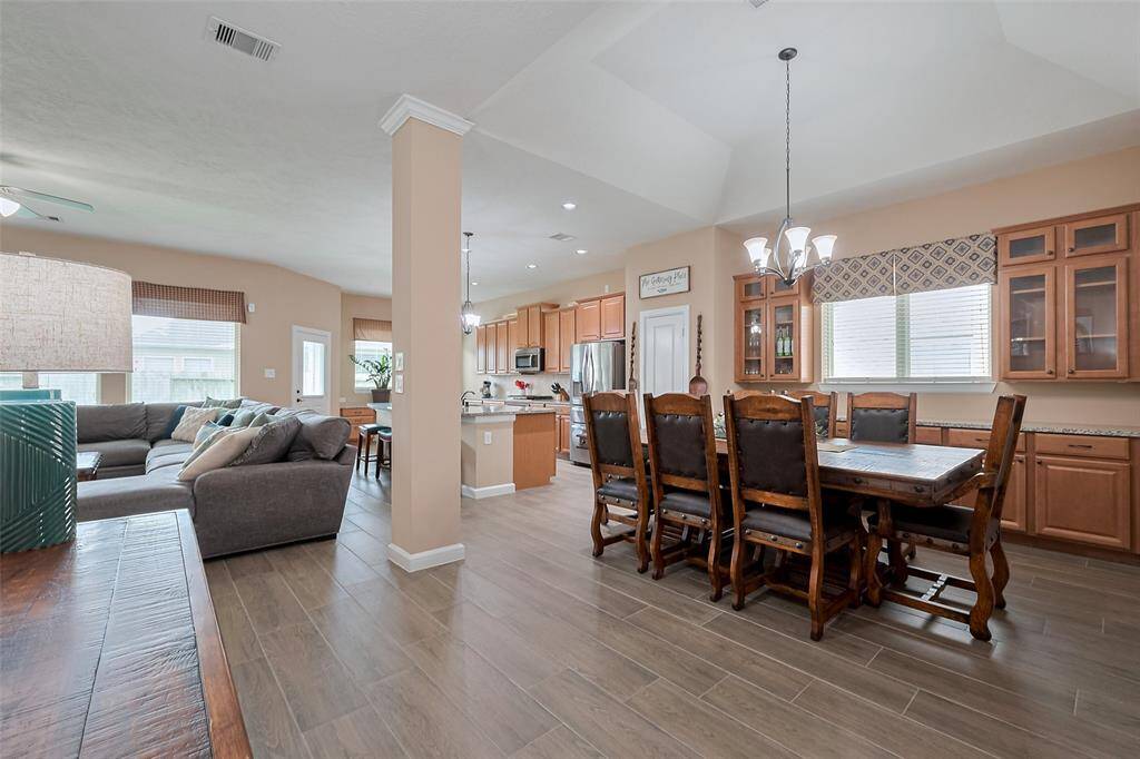 This open-concept living area features a modern kitchen with stainless steel appliances, a spacious dining area and a cozy living room with ample natural light. The neutral tones and wood-look flooring create a warm, inviting atmosphere.