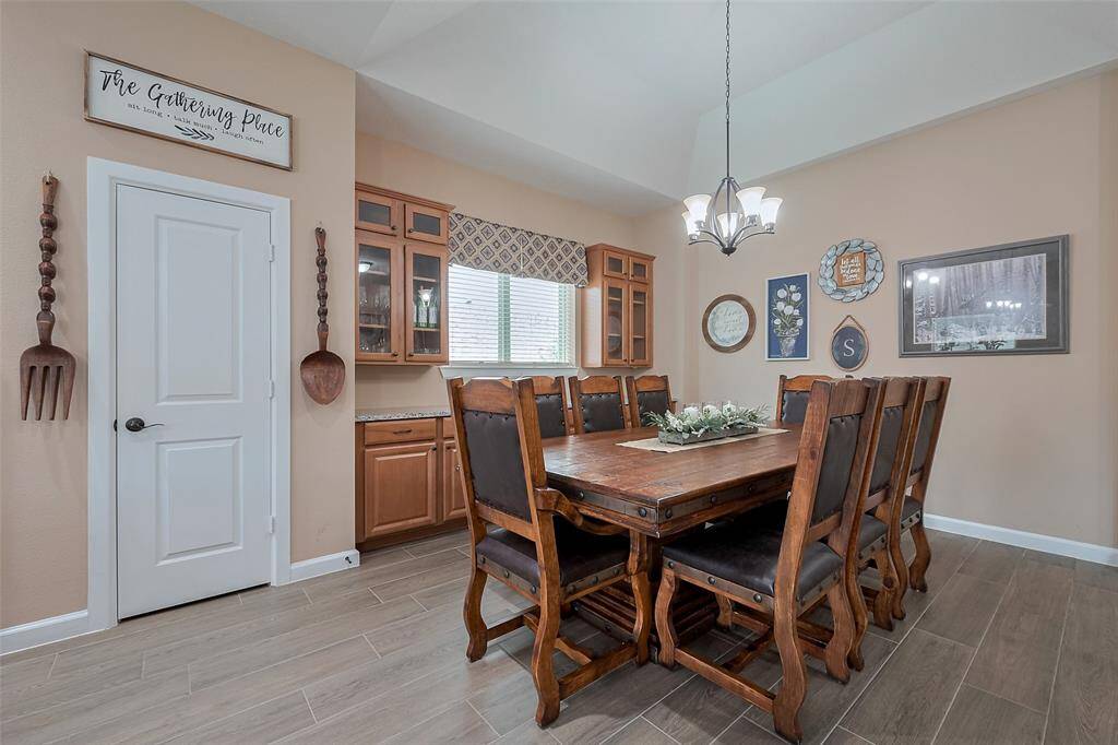 This dining room features a modern chandelier, and built-in cabinetry. The decor is warm and inviting. Natural light streams in through the windows.