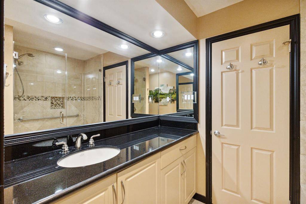 Sleek secondary bathroom featuring granite countertops.