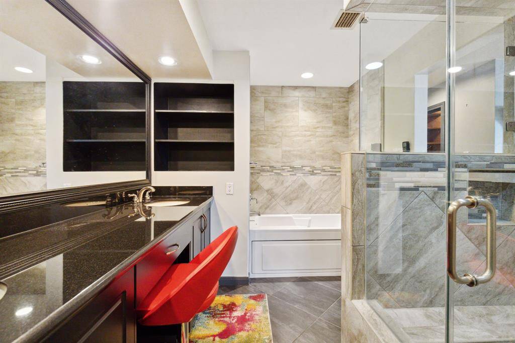 Modern, primary bathroom featuring a large walk-in shower with glass enclosure, double vanity with ample storage, and stylish fixtures.