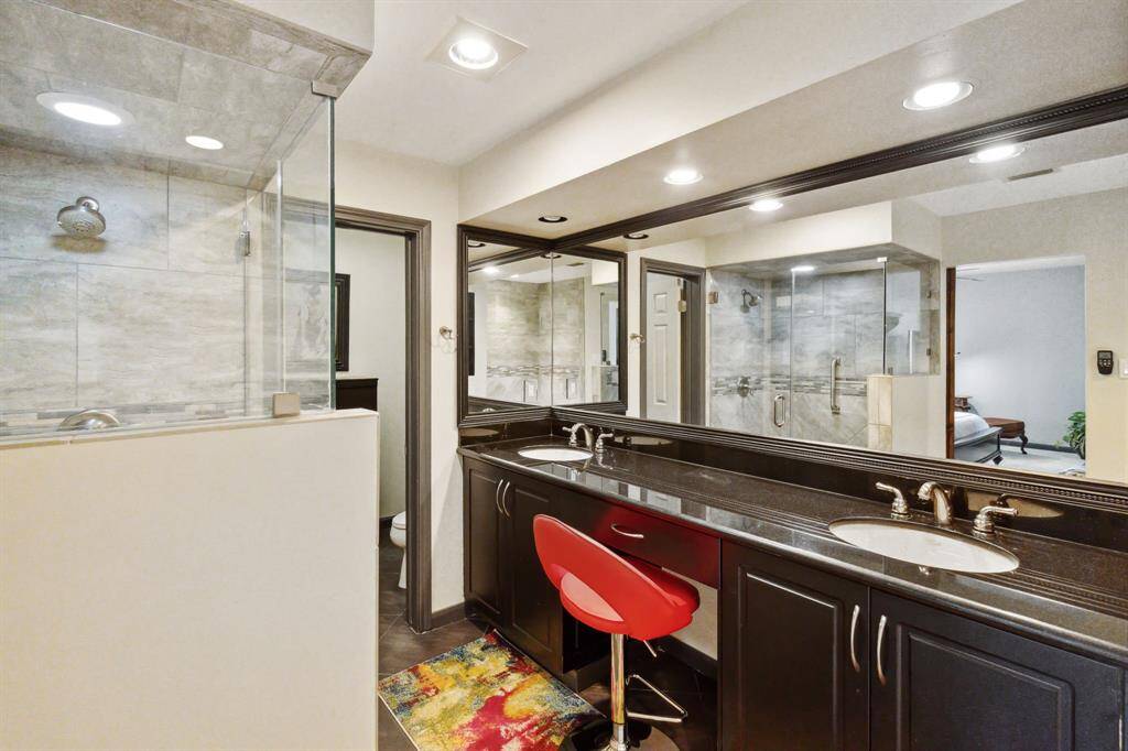 Primary bathroom is accented with stone tile walls and flooring, offering a luxurious feel.