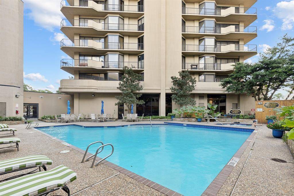 Spacious outdoor pool area complete with sun loungers and shaded seating, offering an inviting communal space for residents.