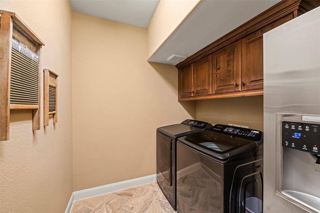 Laundry room with cabinets and plenty of space for an extra refrigerator.