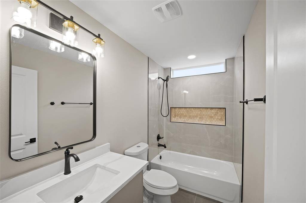 This secondary bathroom is complete with quartz countertops and backsplash, and a shower/tub combo.