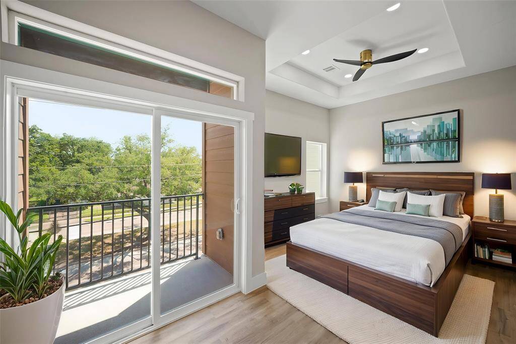 Virtually Staged: Unwind after a long day in this incredible primary bedroom! Featuring vinyl plank floors, a tray ceiling with a ceiling fan, and a private balcony.