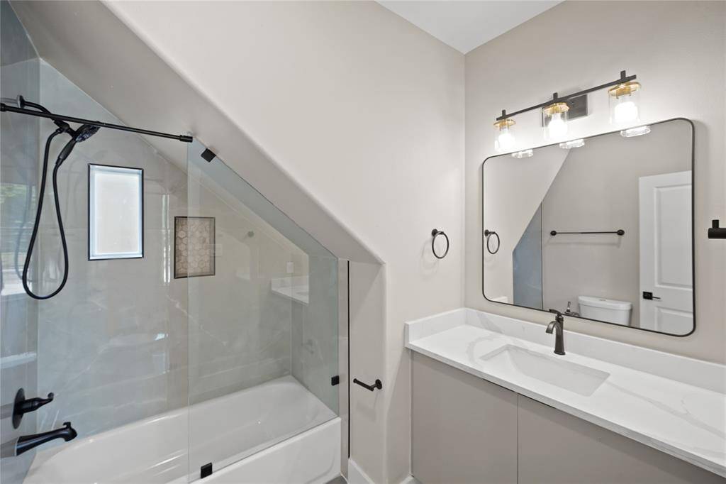This secondary bathroom is complete with quartz countertops and backsplash, and a shower/tub combo.