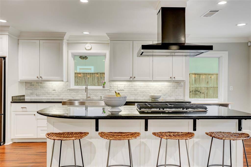 The Kitchen also features a farmhouse stainless-steel sink with polished nickel faucet, a large island with breakfast bar, pots & pans drawers, hidden under-cabinet outlets, bamboo floors, recessed LED lights, crown molding and large windows overlooking the wonderful backyard.