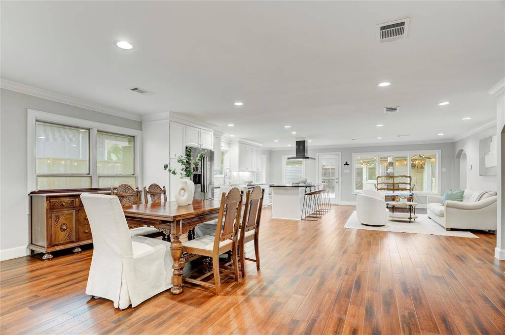 The spacious and open Dining Room, conveniently situated between the Family Room & Kitchen, features bamboo floors, recessed LED lights, large windows overlooking the spacious side yard and crown molding.