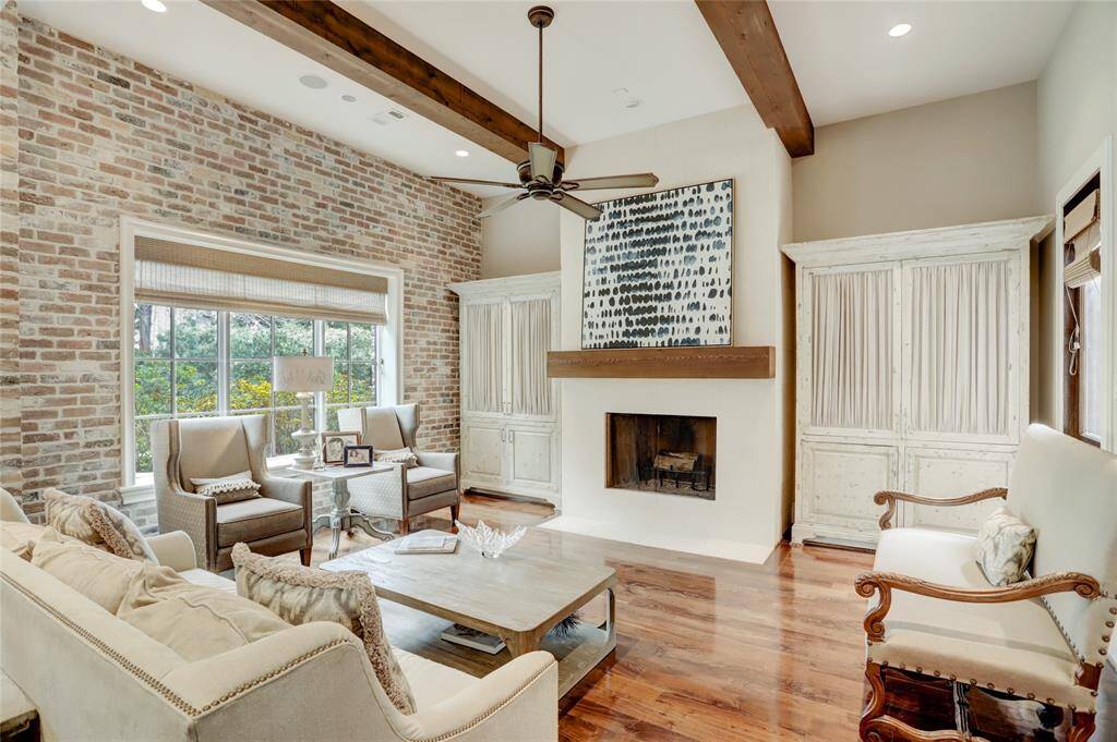 Beautiful brick accented wall in the family room with wood beams and natural light from wall of windows leading to the breakfast room and kitchen