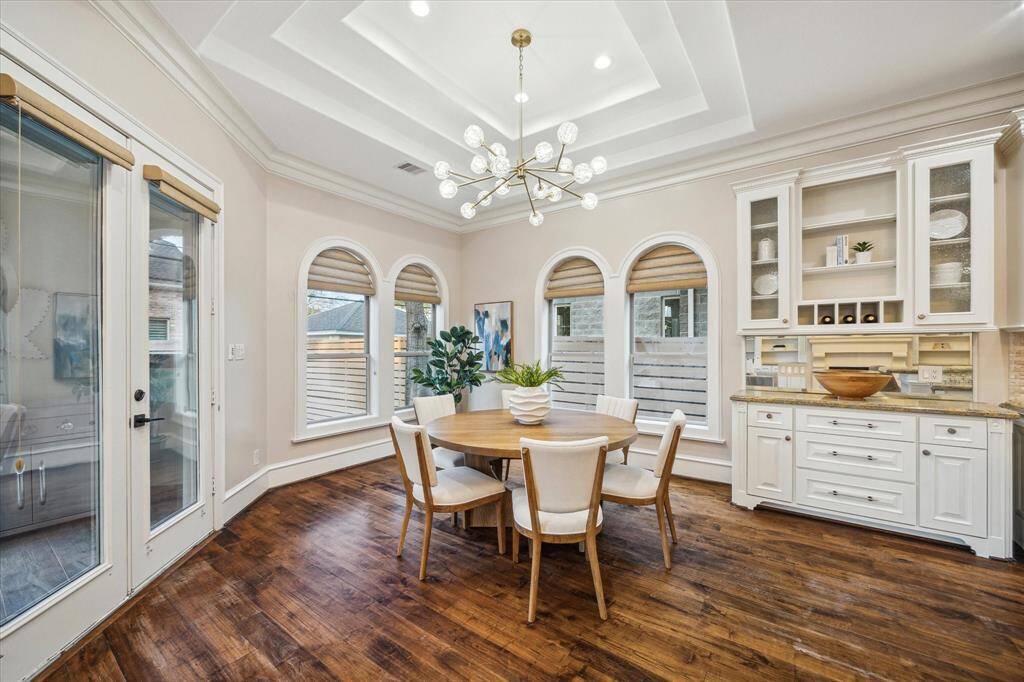 This space features a convenient buffet with granite countertop, a dramatic tray ceiling,  and abundant natural light.