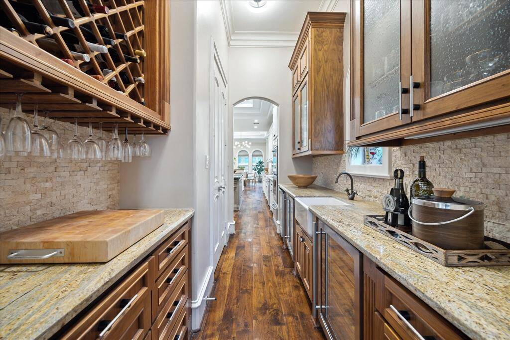 The butler's pantry sits conveniently between the dining room and kitchen and provides wine storage (25+ bottles), a secondary sink, walnut glass-front cabinetry, and serving counters. To the left sits a walk-in pantry with abundant shelving.