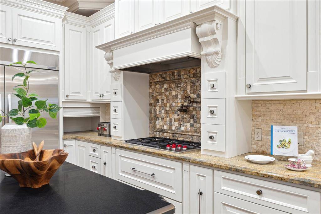 Striking corbels and spice storage frame the Wolf gas cook-top, while a convenient pot filler and appliance garage provide another thoughtful details.