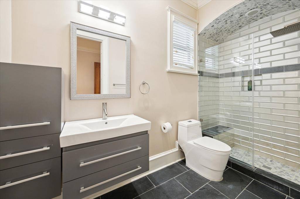 Recently updated, the secondary bathroom located in the sitting area adjacent to the primary bedroom features a frameless glass shower and glass subway tile.