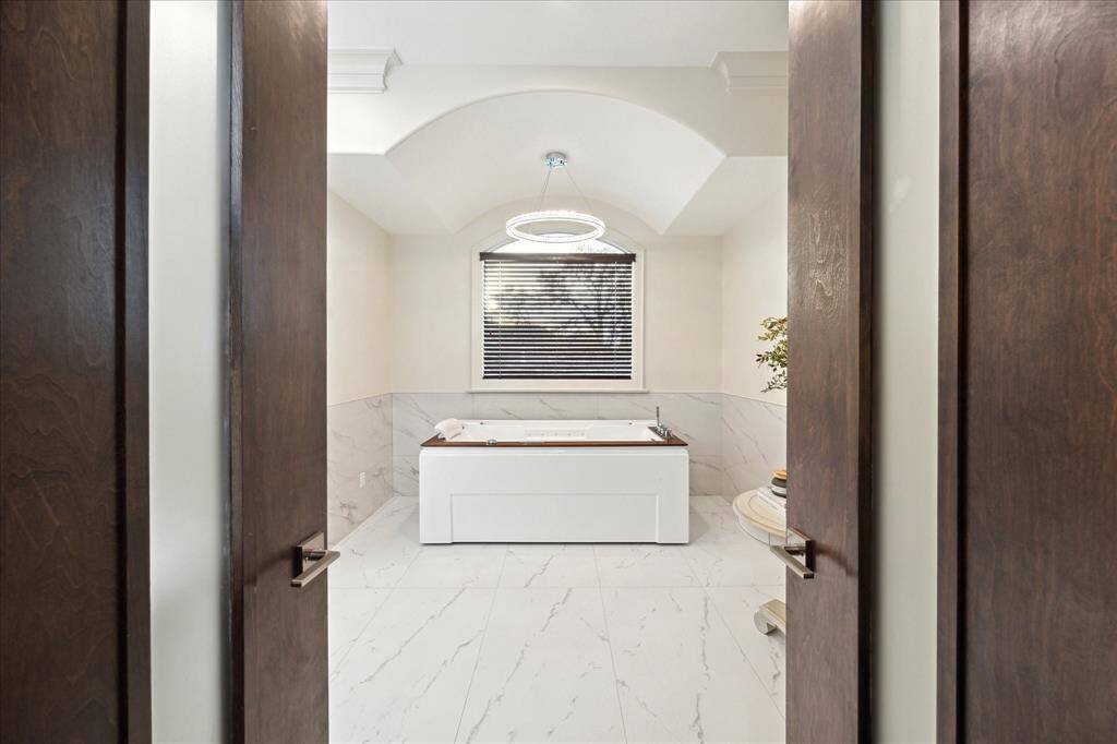 Beyond French doors lies the spa-like bath, complete with a therapeutic soaking tub.