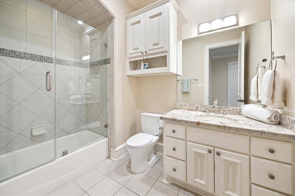 This en-suite bath features granite counters and a glass-enclosed tub.