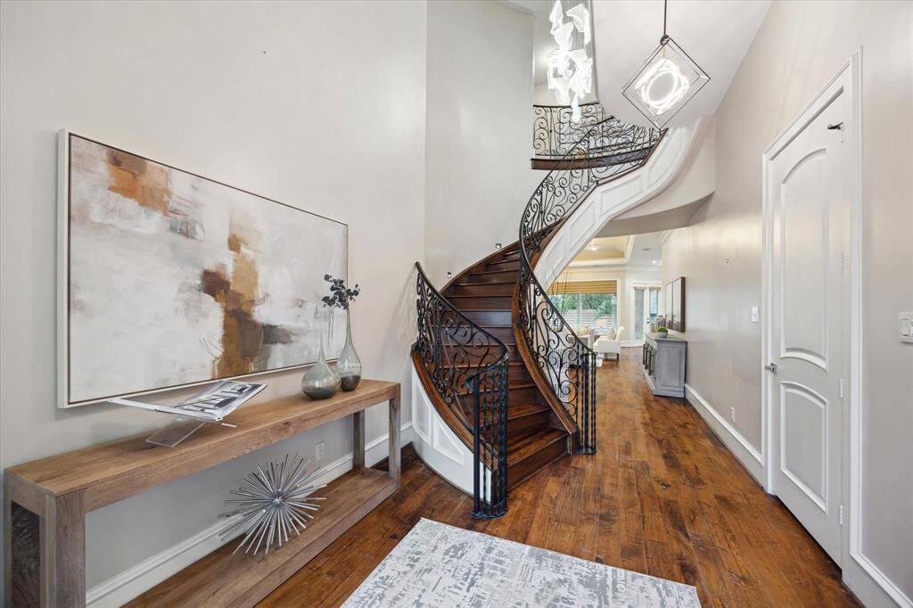 The breathtaking foyer offers a soaring ceiling, rich walnut flooring, and a sweeping spiral staircase with walnut treads.