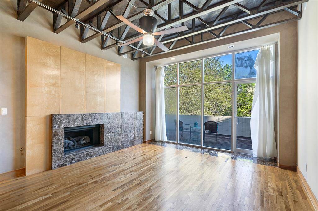 Modern Living space (approx. 17x15)features high ceilings, exposed stainedtrusses, marble surround gas logfireplace, floor to ceiling commercialwindows to private terrace, ceiling fan,oak hardwood flooring.