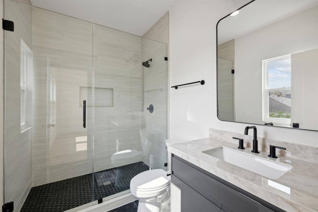 Ensuite bath with frameless shower and designer tile.