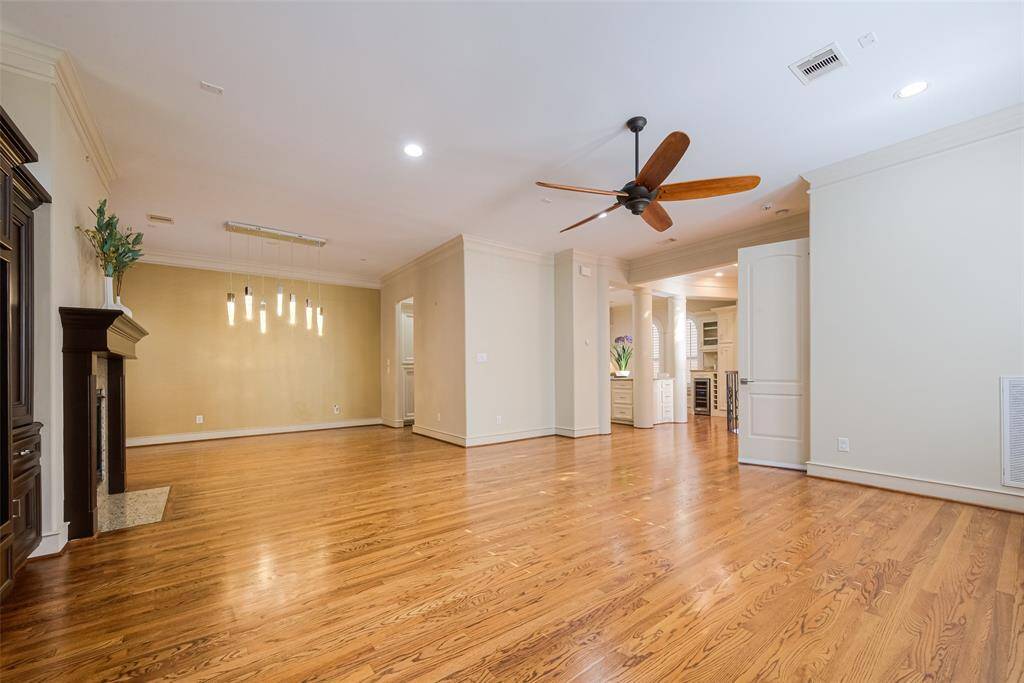 Spacious dining area with hardwood floors, a ceiling fan, and a cozy fireplace. It features an open layout that flows into the kitchen, accented by modern pendant lighting and ample natural light.