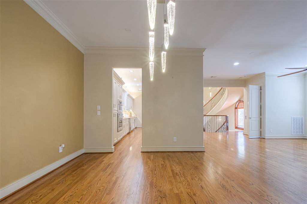 This photo showcases a spacious dining area, open-concept living area with hardwood floors, elegant lighting, and a view into a modern kitchen and a grand staircase. The neutral color palette enhances the natural light, creating a warm and inviting atmosphere.