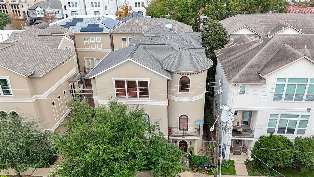 This aerial view of the home showcases a bustling urban neighborhood with a mix of modern and traditional homes. The area is densely populated, featuring tree-lined streets.