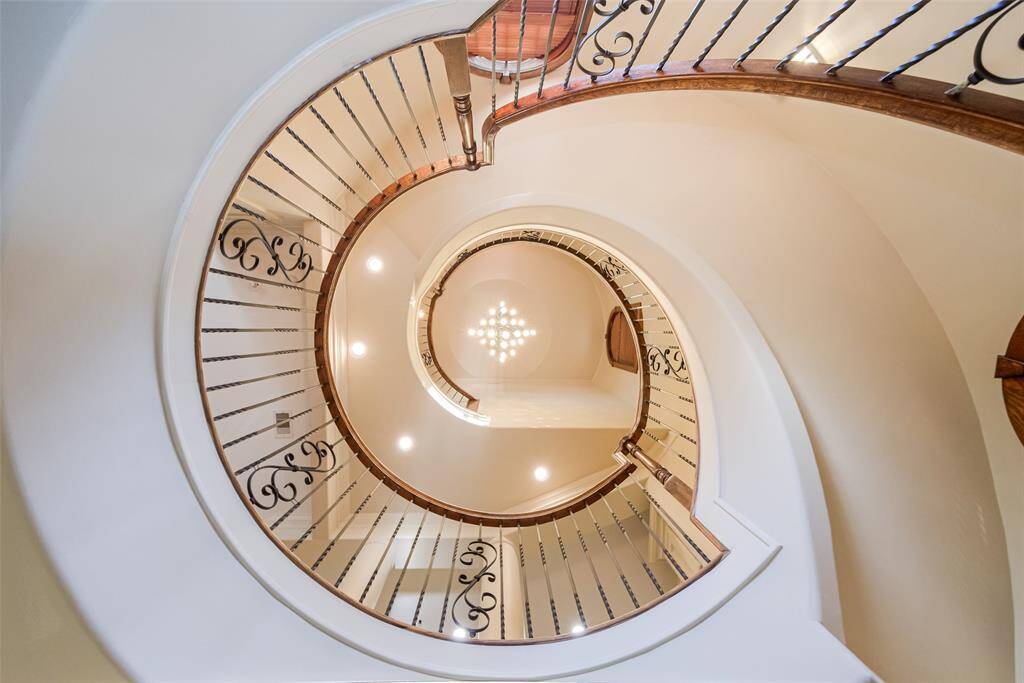 The stunning spiral staircase with elegant wrought iron railings creates a dramatic architectural focal point in the home.