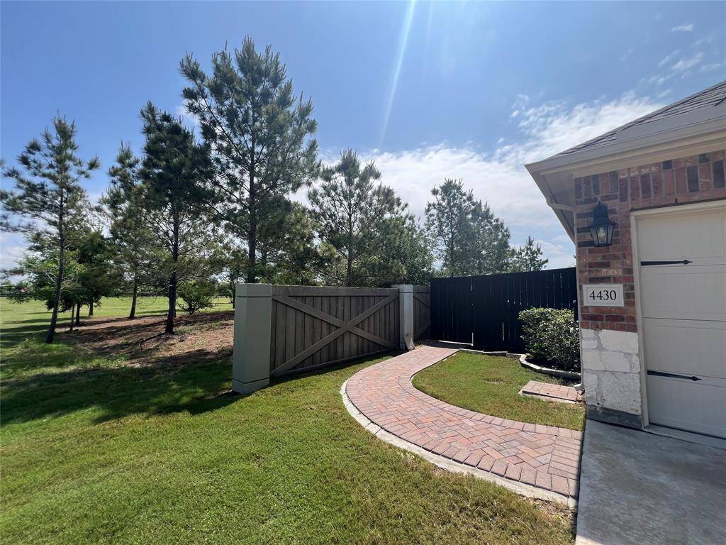 View of front side of home. Paved walkway to the backyard, beautiful wooded green space to the left.