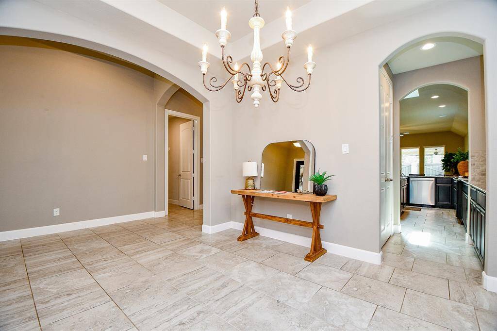 Elegant formal dinning room with upgraded light fixture & leading to kitchen.