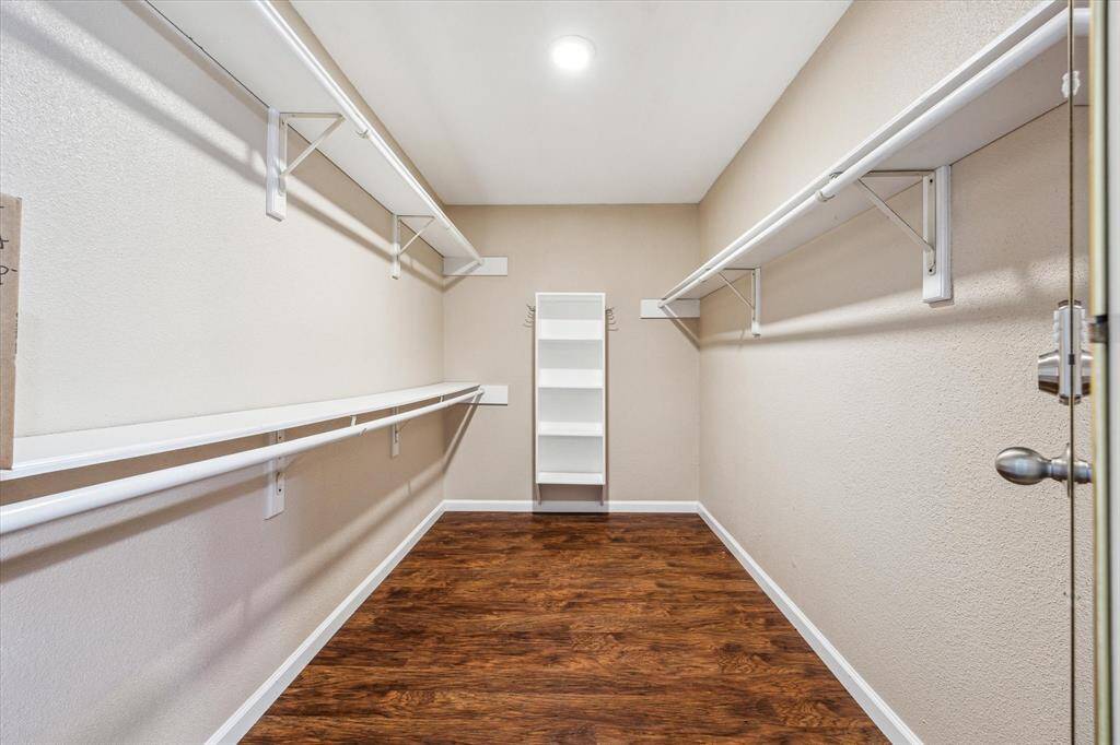 Spacious primary closet with shelving and hanging racks.