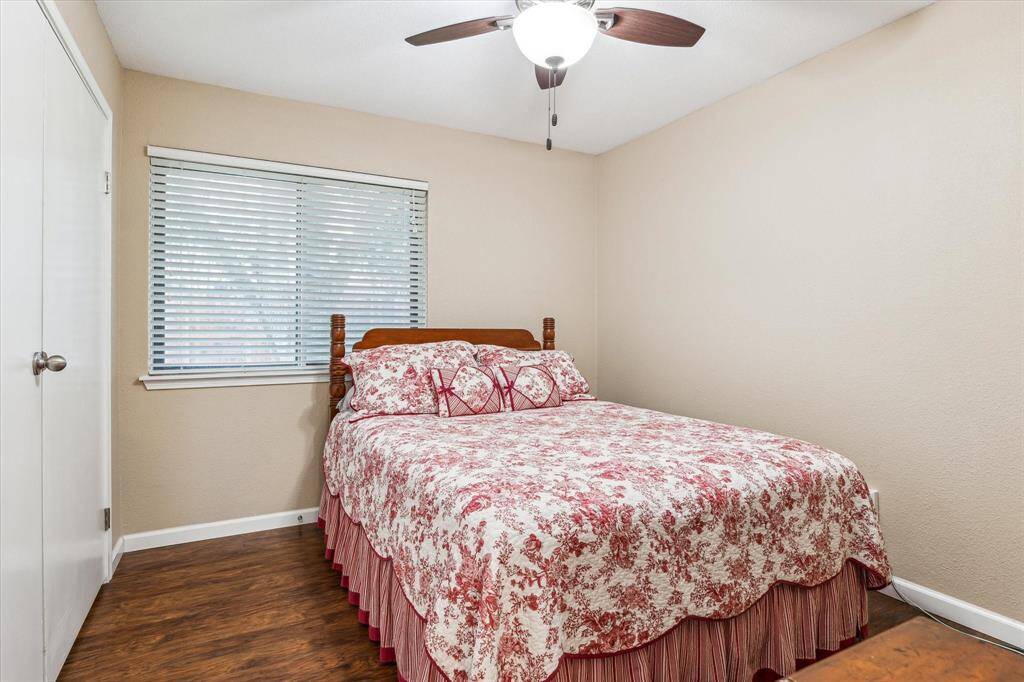 A secondary bedroom with a ceiling fan and a large window.