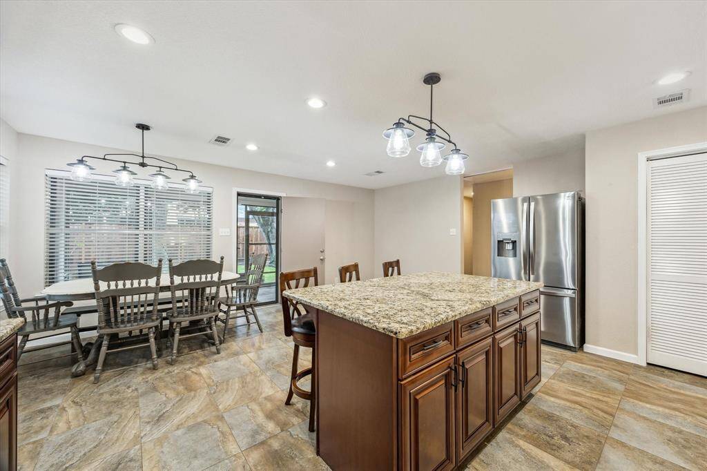 This view showcases the modern light fixtures and large kitchen windows overlooking the sunroom & backyard.