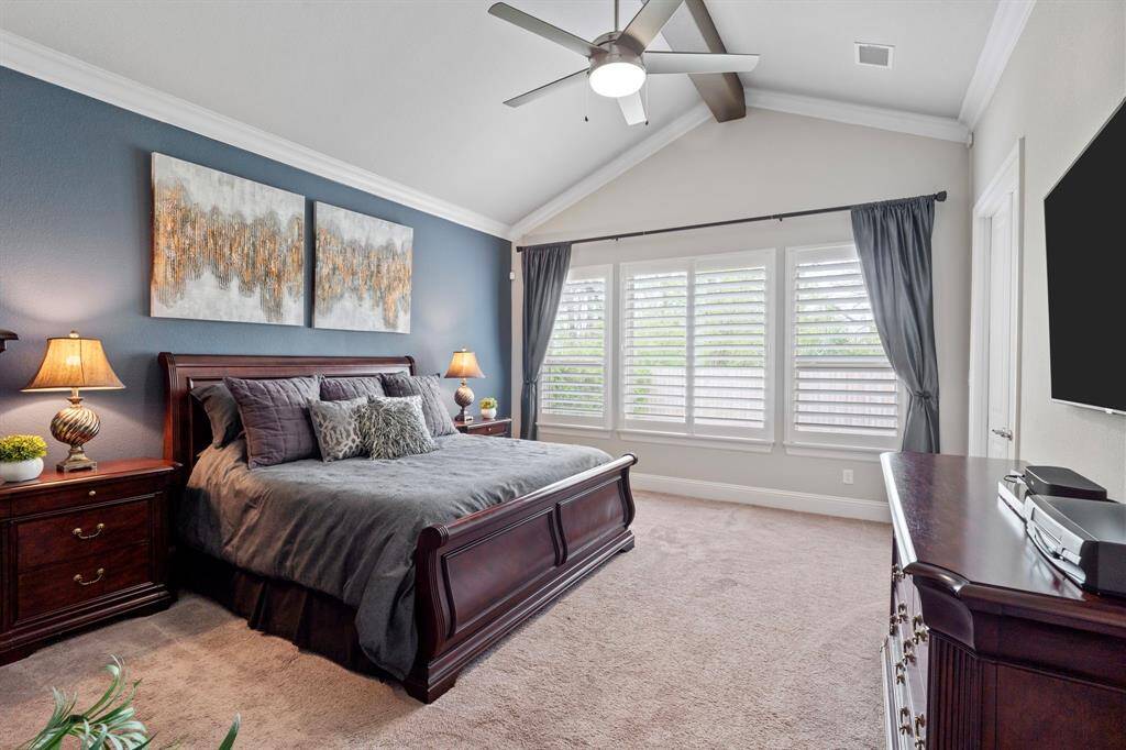 Primary bedroom features a vaulted ceiling, crown molding and beam
