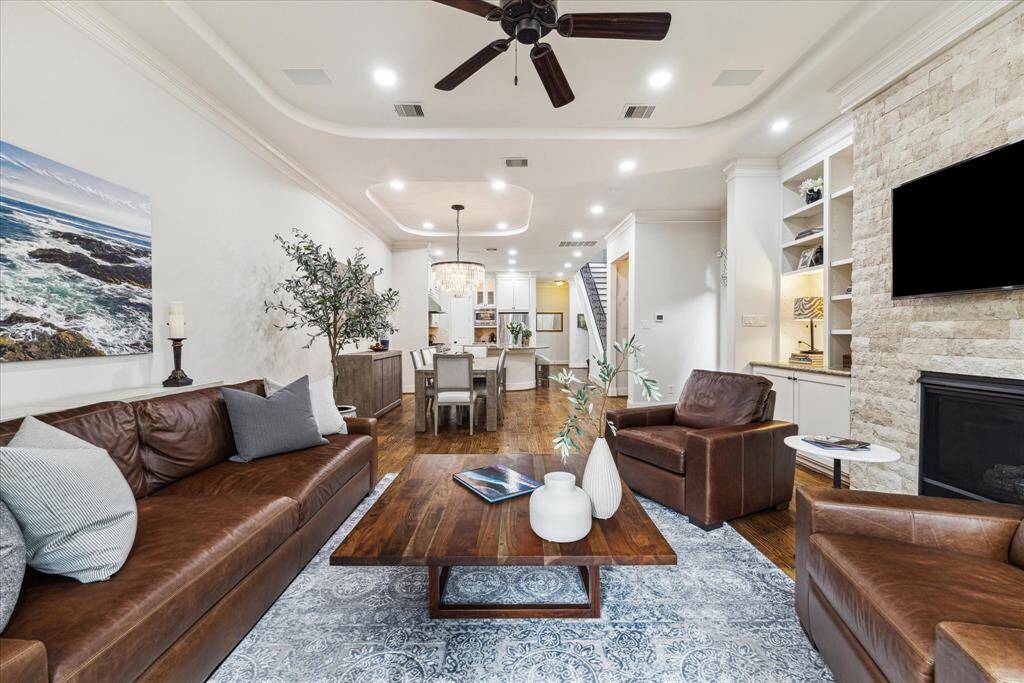 The living room flows seamlessly into a dining area and kitchen and is complemented by a high, curved tray ceiling.