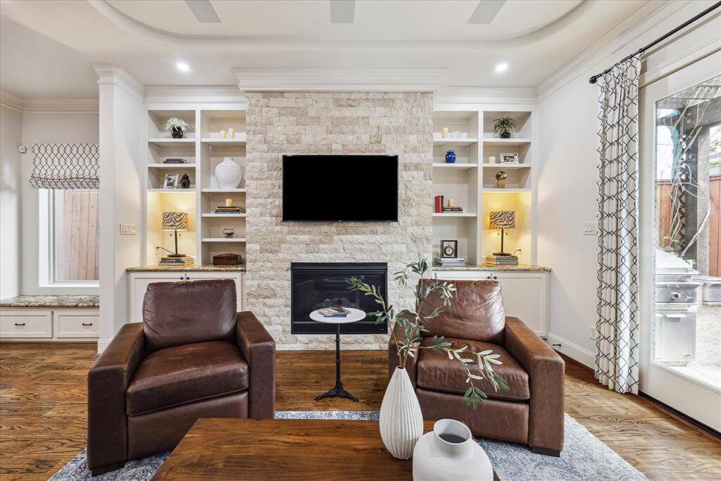 Living room features adjustable shelving, gas fireplace with a textured stone accent wall and built-in speakers.