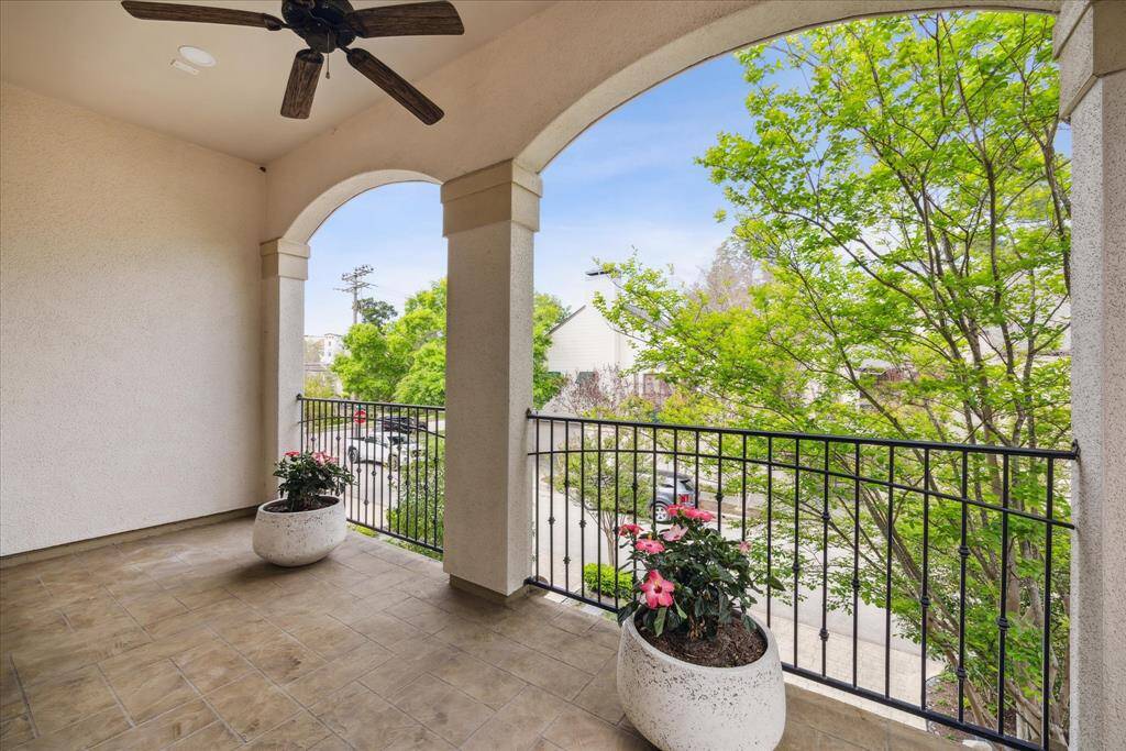 A spacious covered balcony off the primary bedroom, featuring a ceiling fan and arched doorways that add architectural charm.
