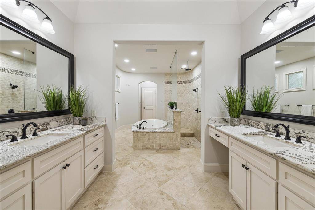 The primary bath features a double vanity, expansive granite countertops, and two large framed mirrors, creating a spa-like atmosphere for daily routine.