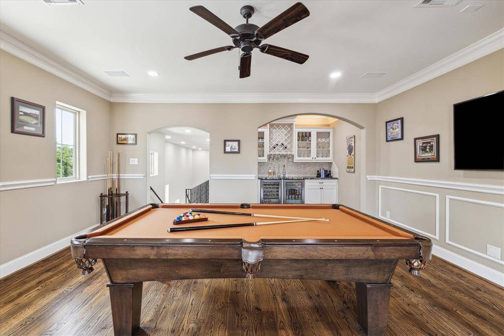 The game room also features a wet bar area with a wine and beverage cooler, sink, granite countertop, cabinetry, and a wine rack.