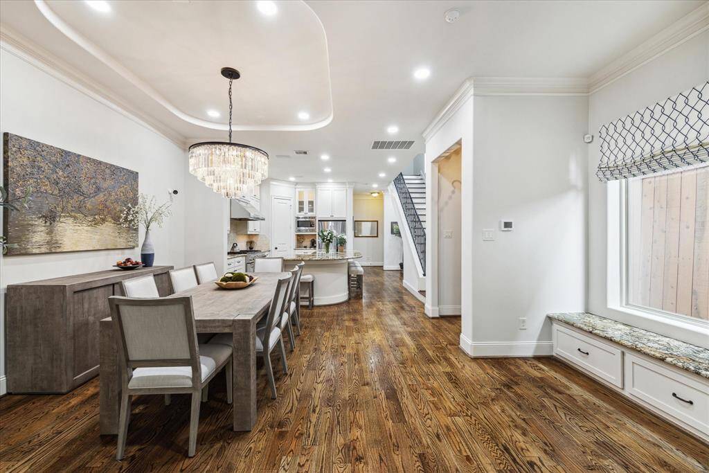 A spacious dining room with ample space for a buffet table, featuring a tray ceiling and an elegant RH chandelier.