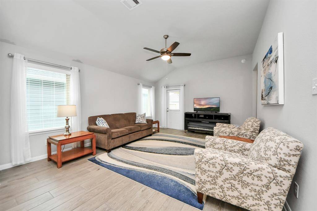 The living room has high ceilings, large windows, ceiling fan, and access to the backyard.
