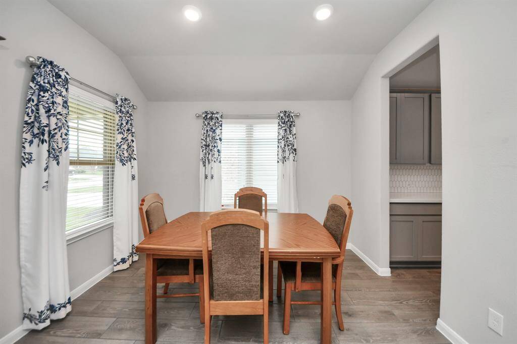 This dining room features large windows, high ceilings, and recessed lighting.