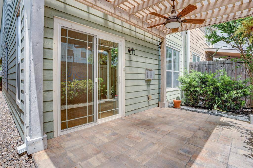 This view of the backyard showcases the connection between indoor and outdoor living, with sliding glass doors leading directly to the covered patio. Whether you're hosting a casual dinner under the string lights or simply unwinding with a cup of coffee, this inviting space offers the perfect blend of comfort and privacy for everyday enjoyment.